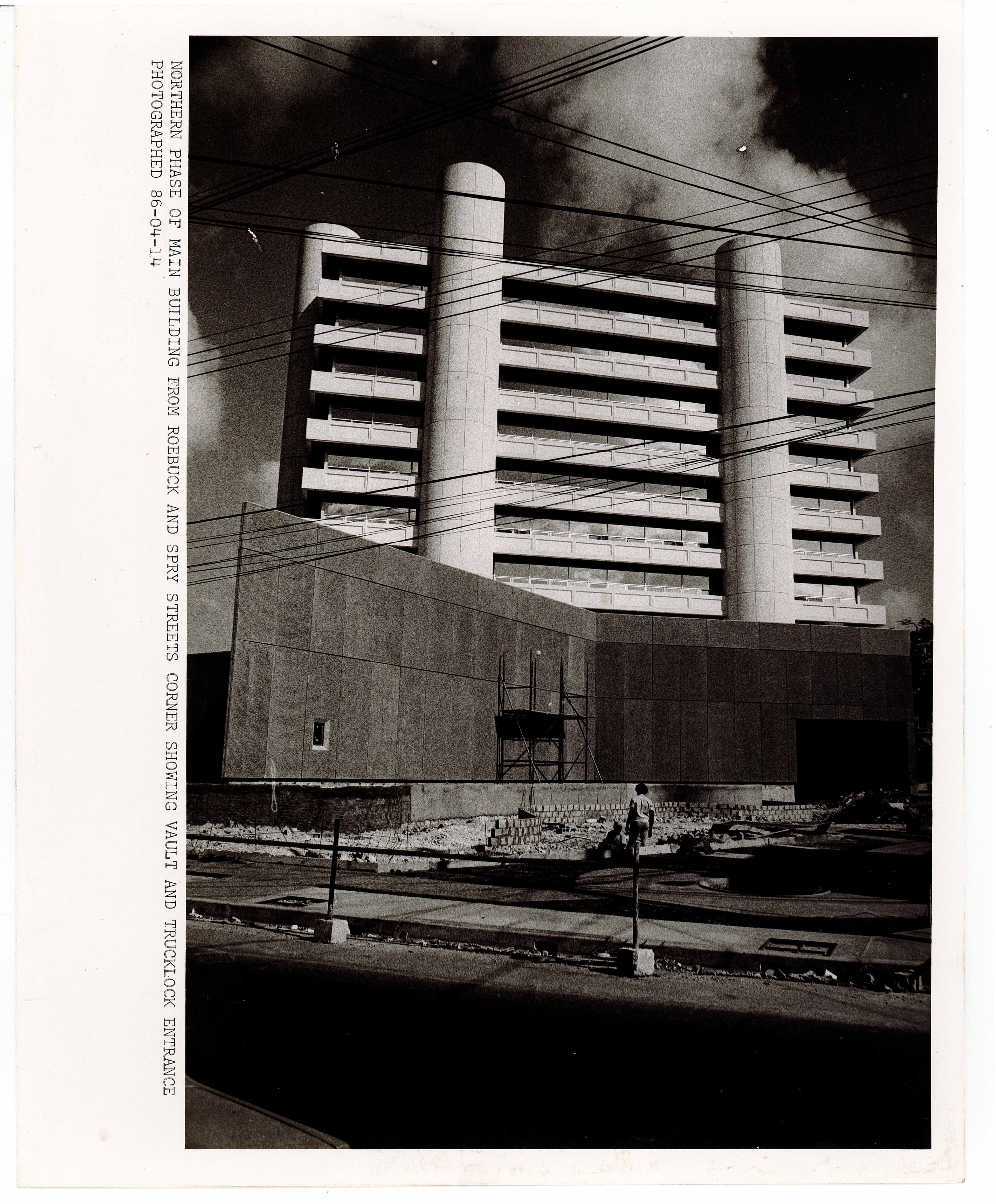 Brutalist concrete building with tall columns and visible floor slabs against a dark sky.