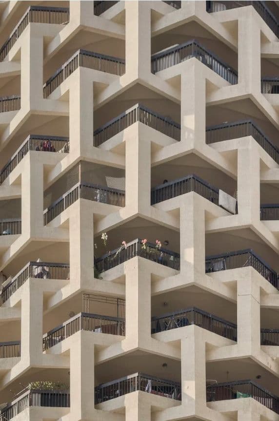 Modern building facade with interlocking geometric concrete patterns and balconies.