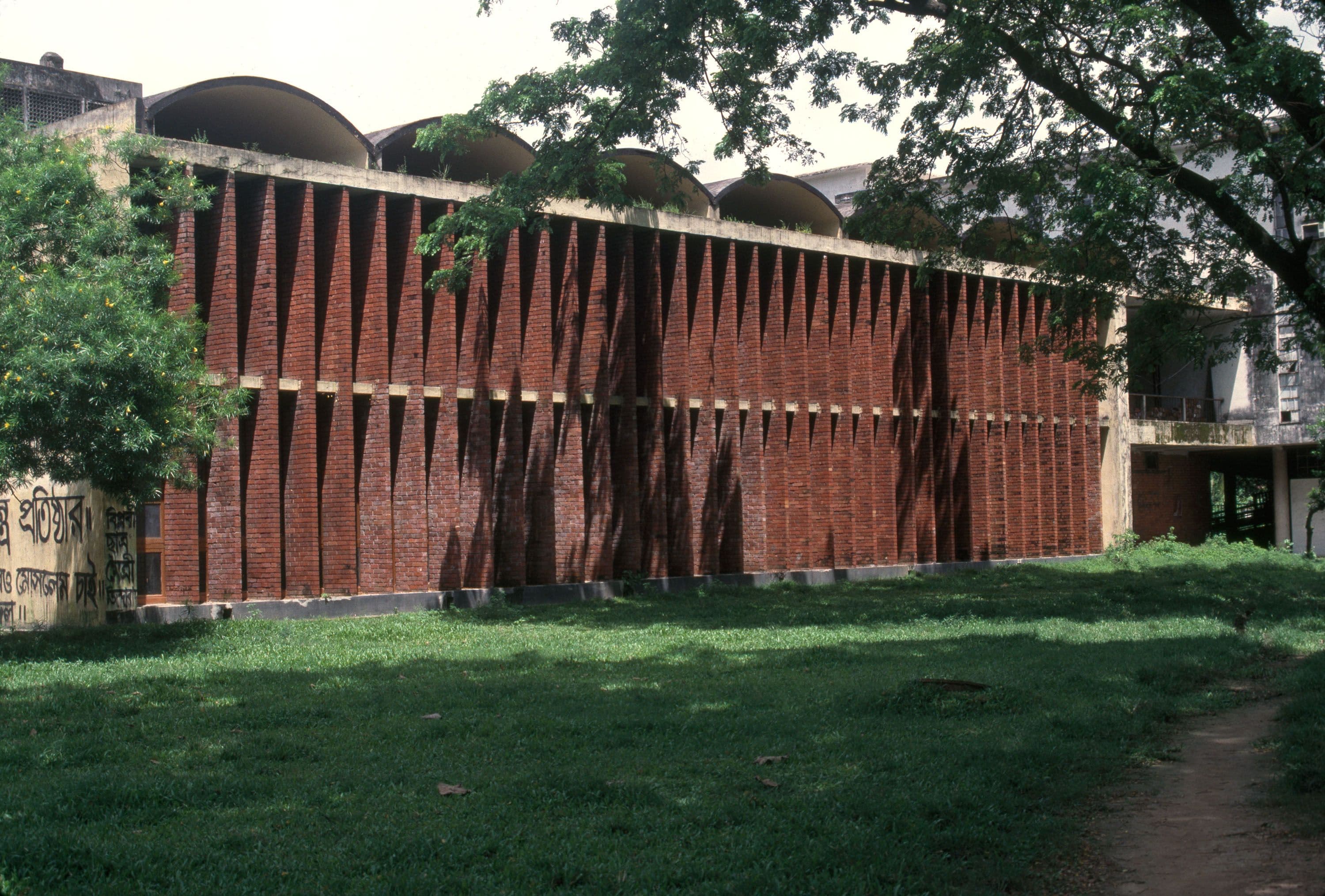 A long, modern building with a facade of vertical brick louvers and domed roof sections.