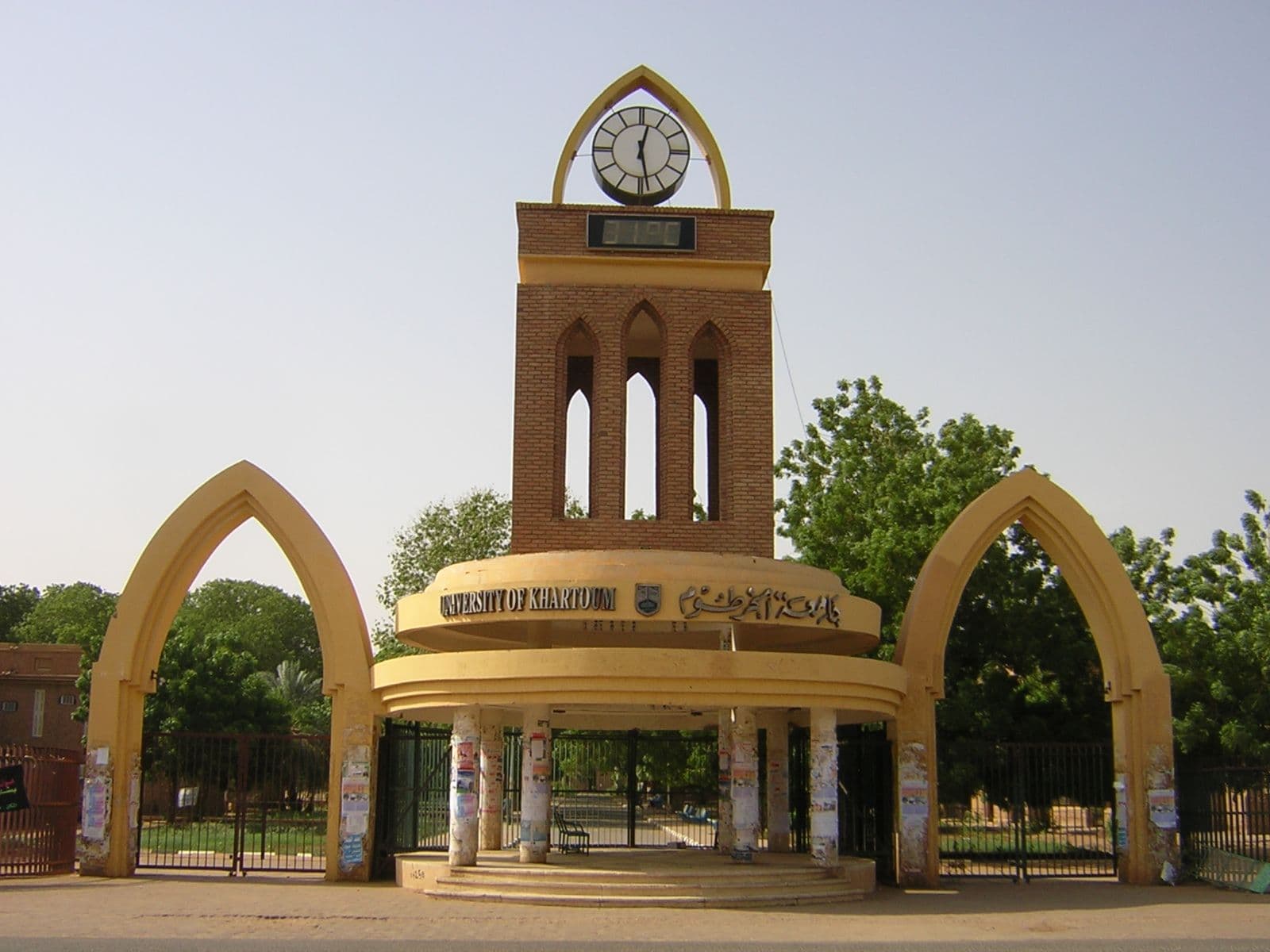 A prominent brick clock tower with a golden domed base and two flanking arched entrances.
