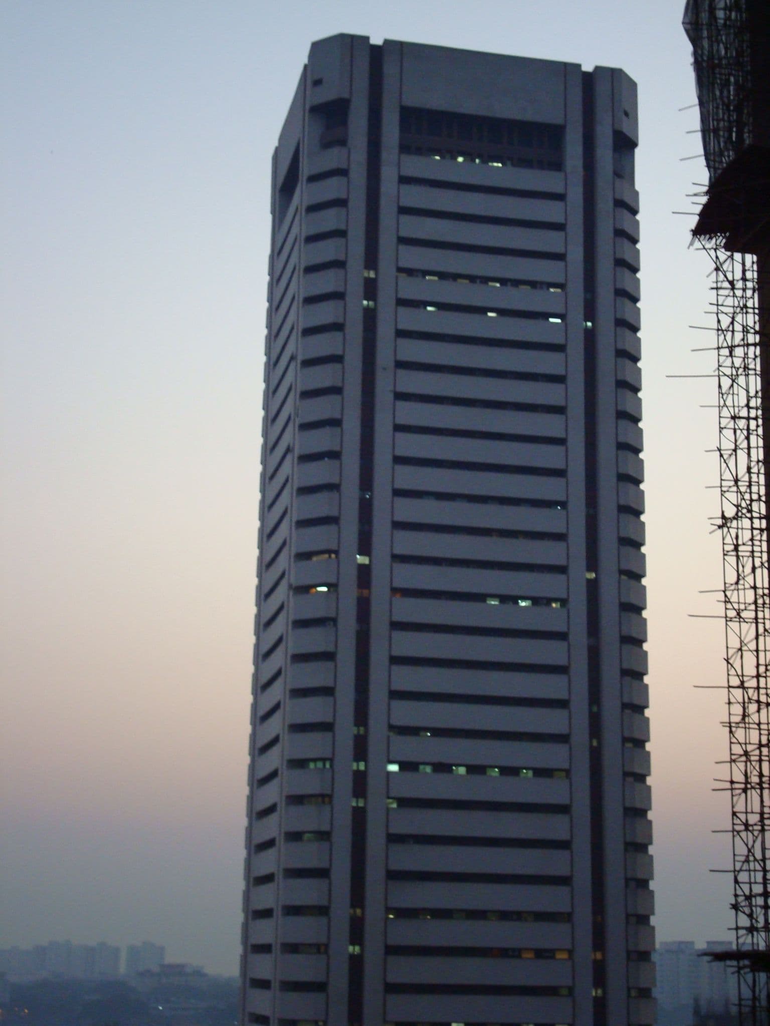 A tall, rectangular skyscraper with horizontal window bands against a soft sky.