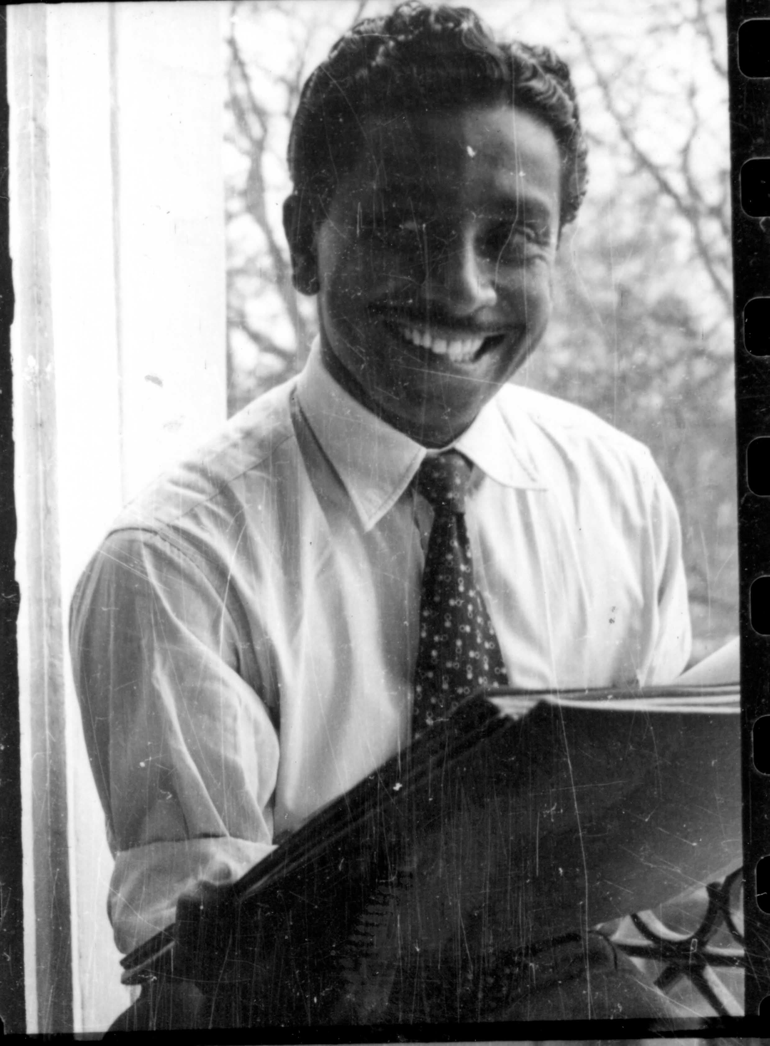 Smiling man in a white shirt and patterned tie looking directly at the camera.