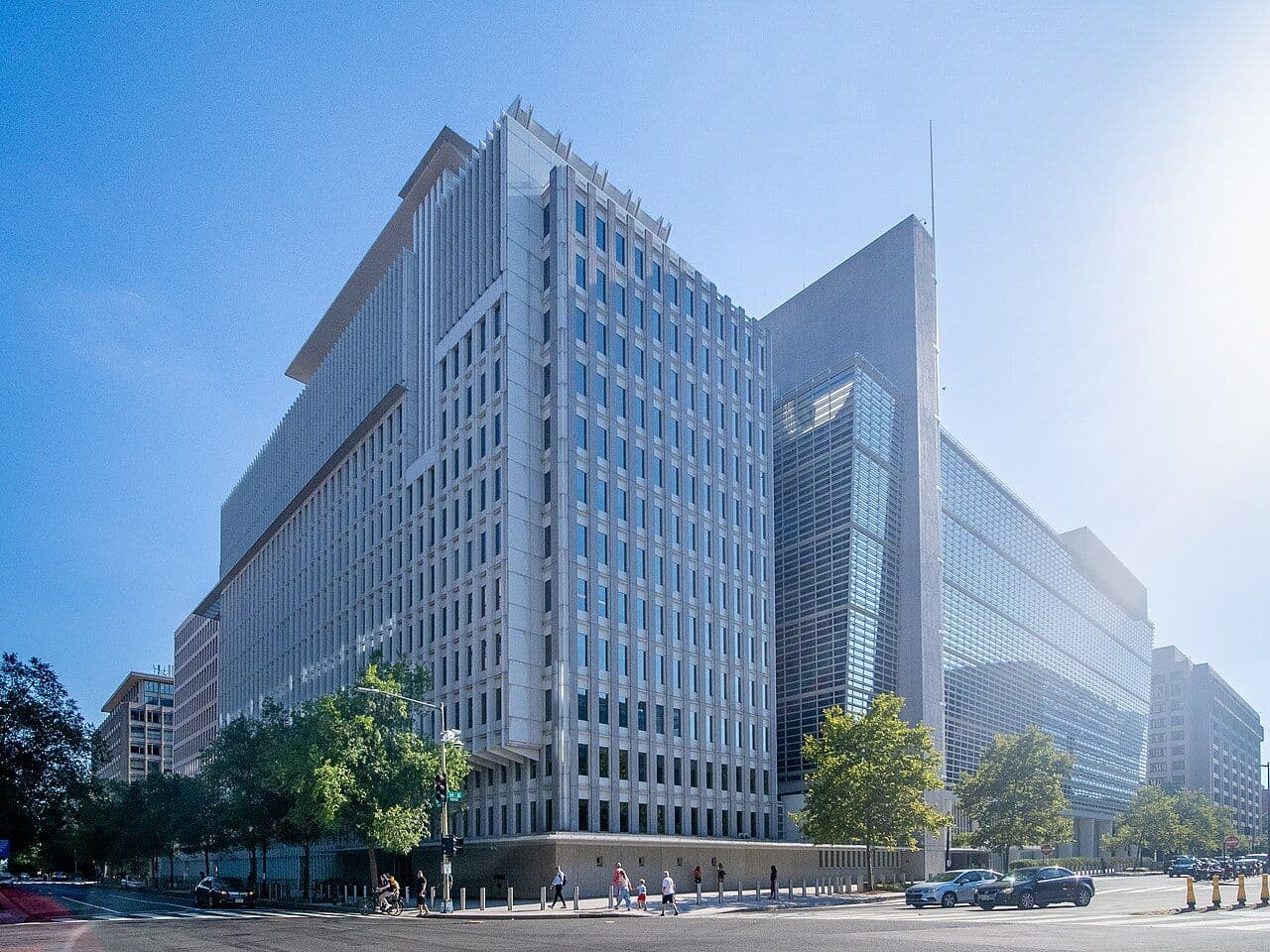 Large modern office building with many windows under a bright blue sky.