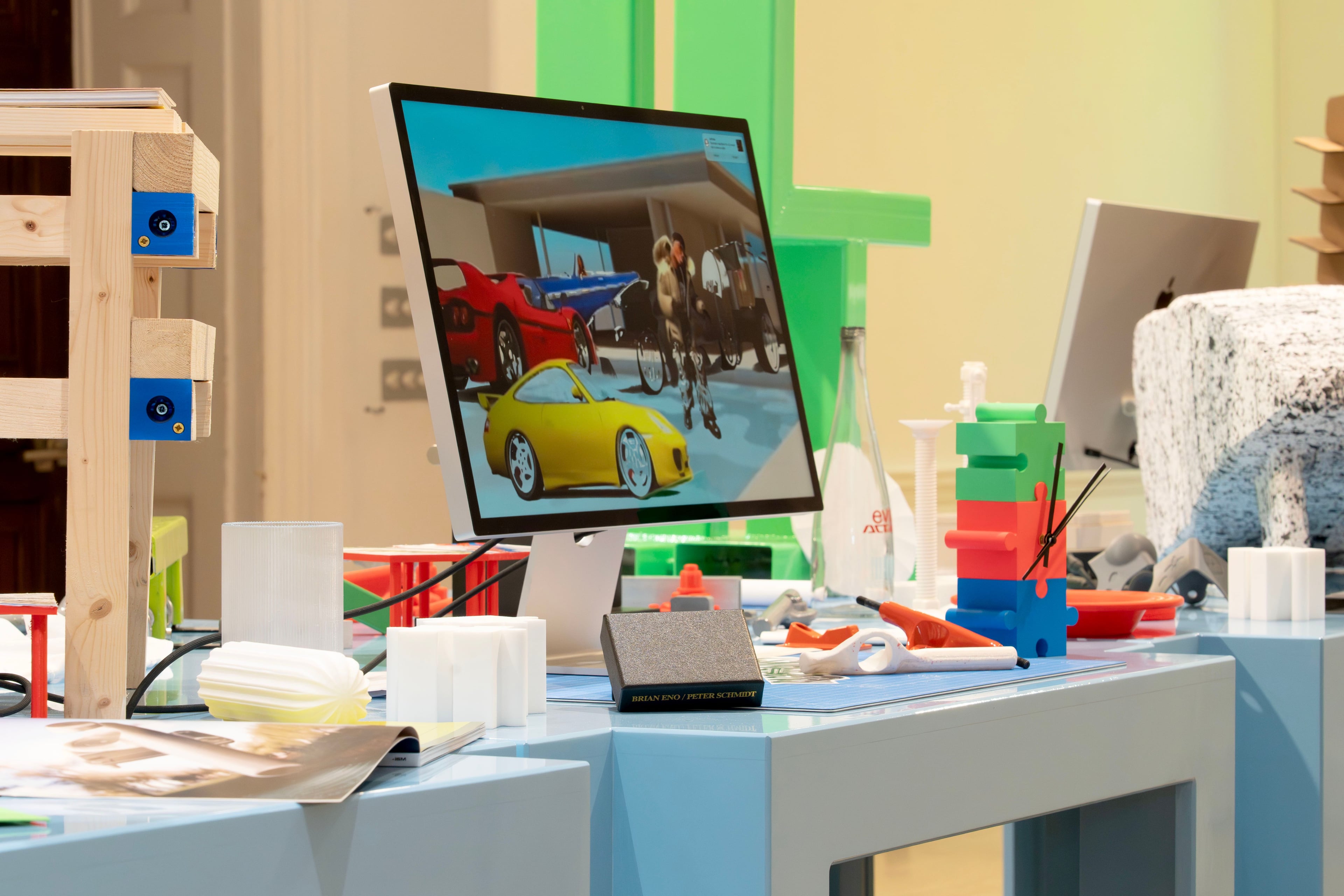 Objects on blue tables, including an iMac display and various product prototypes.
