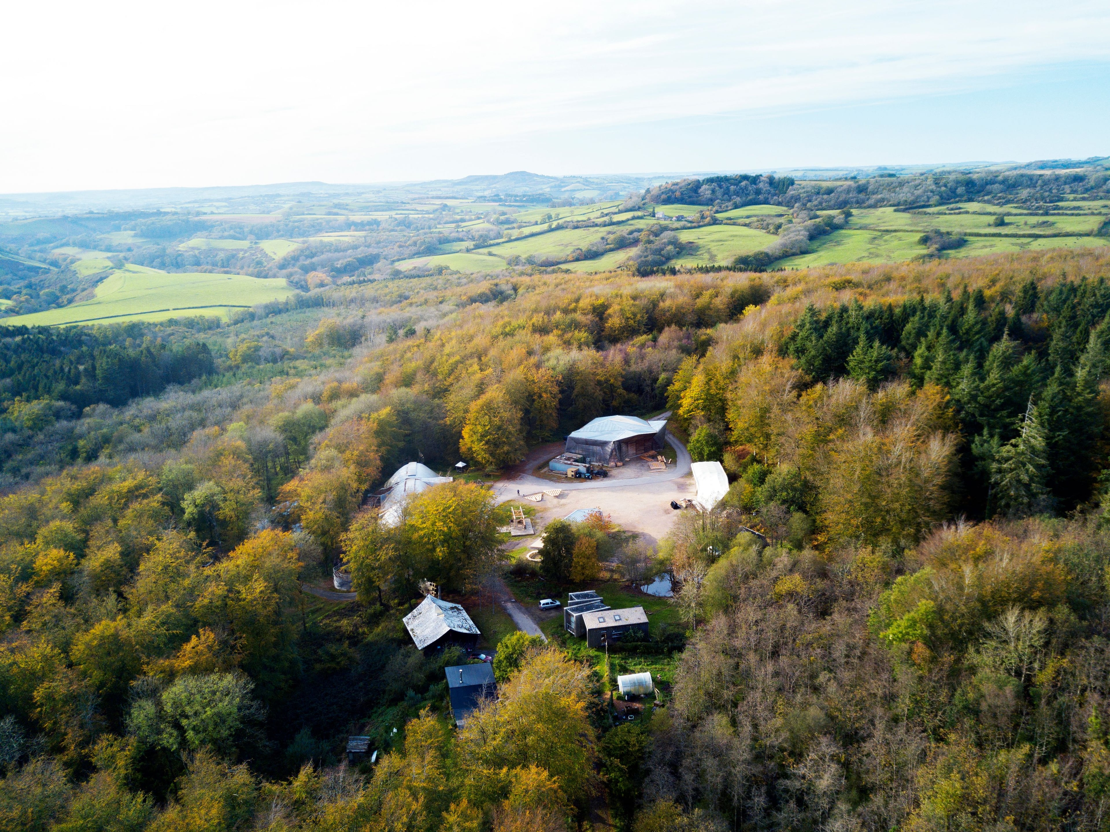 The Hooke Park campus buildings seen from the air, surrounded by woodland and in the wider landscape of the Dorset countryside.