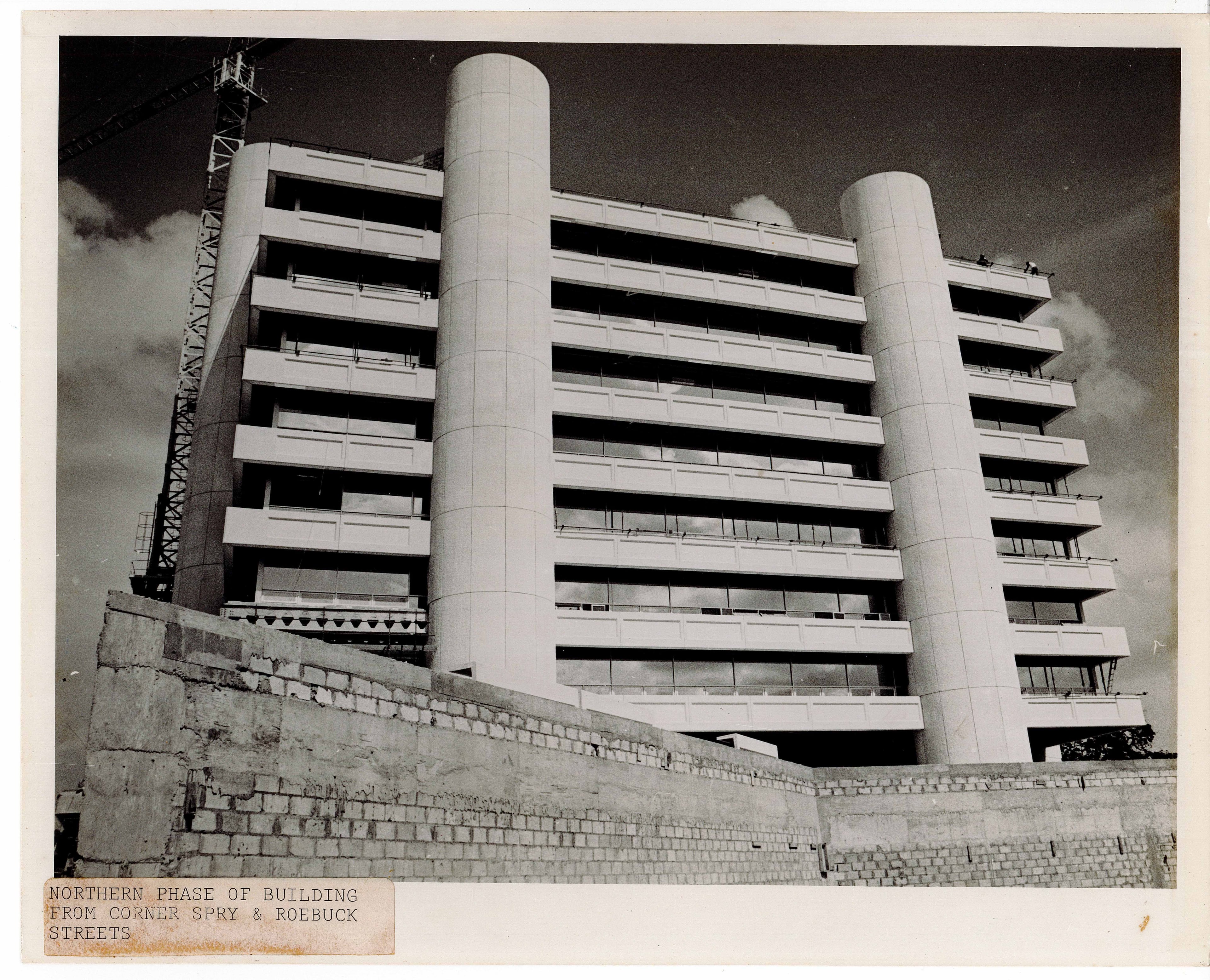 Modern multi-story building under construction with two large cylindrical towers and many balconies.