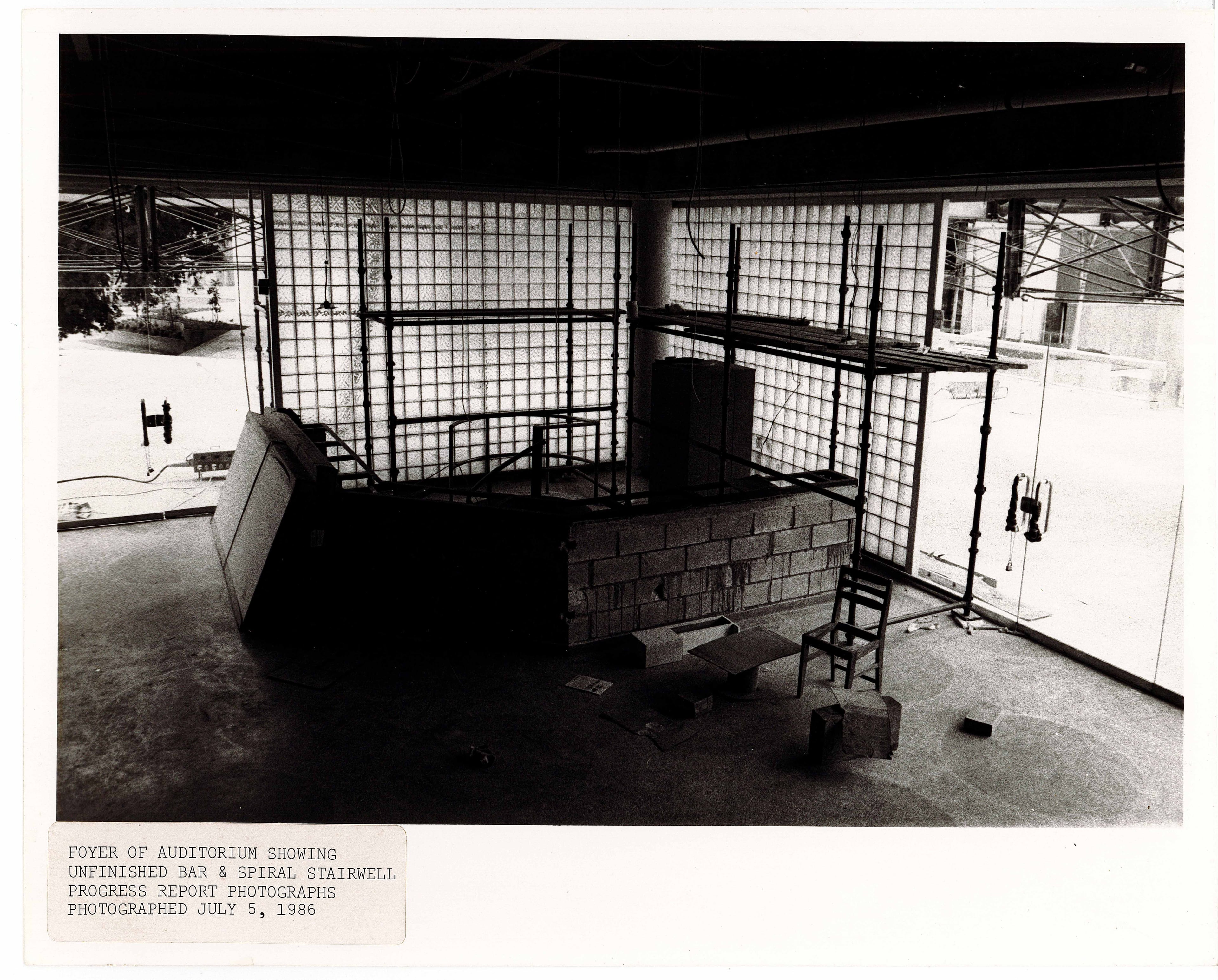 Modern interior space featuring glass block walls, a concrete counter, and two simple chairs.