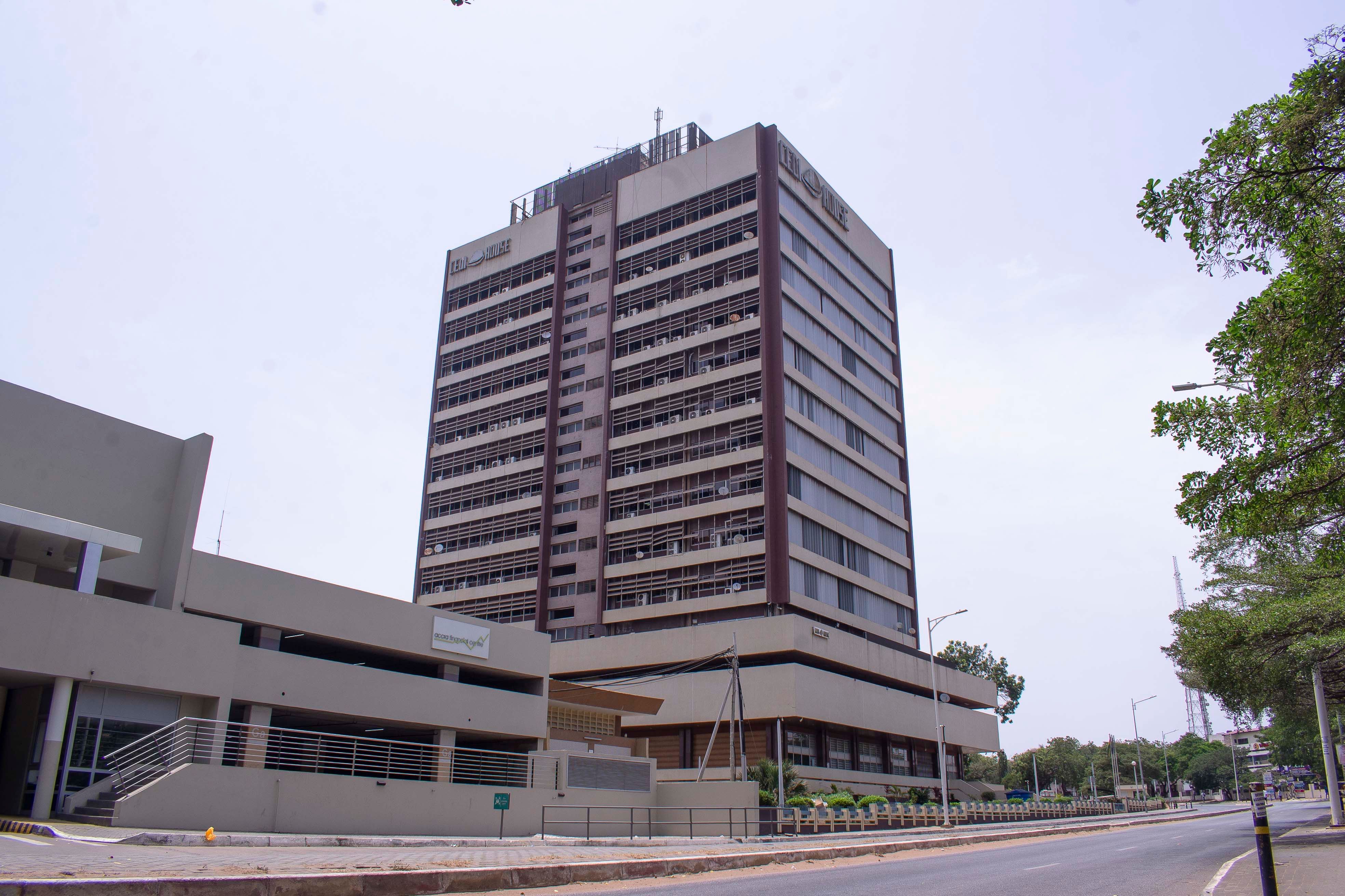 A tall, brown multi-story building stands prominently in a city environment.