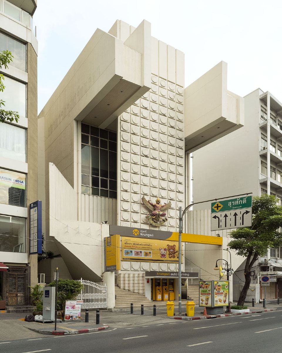 Modern brutalist building with geometric concrete facade and yellow accents.
