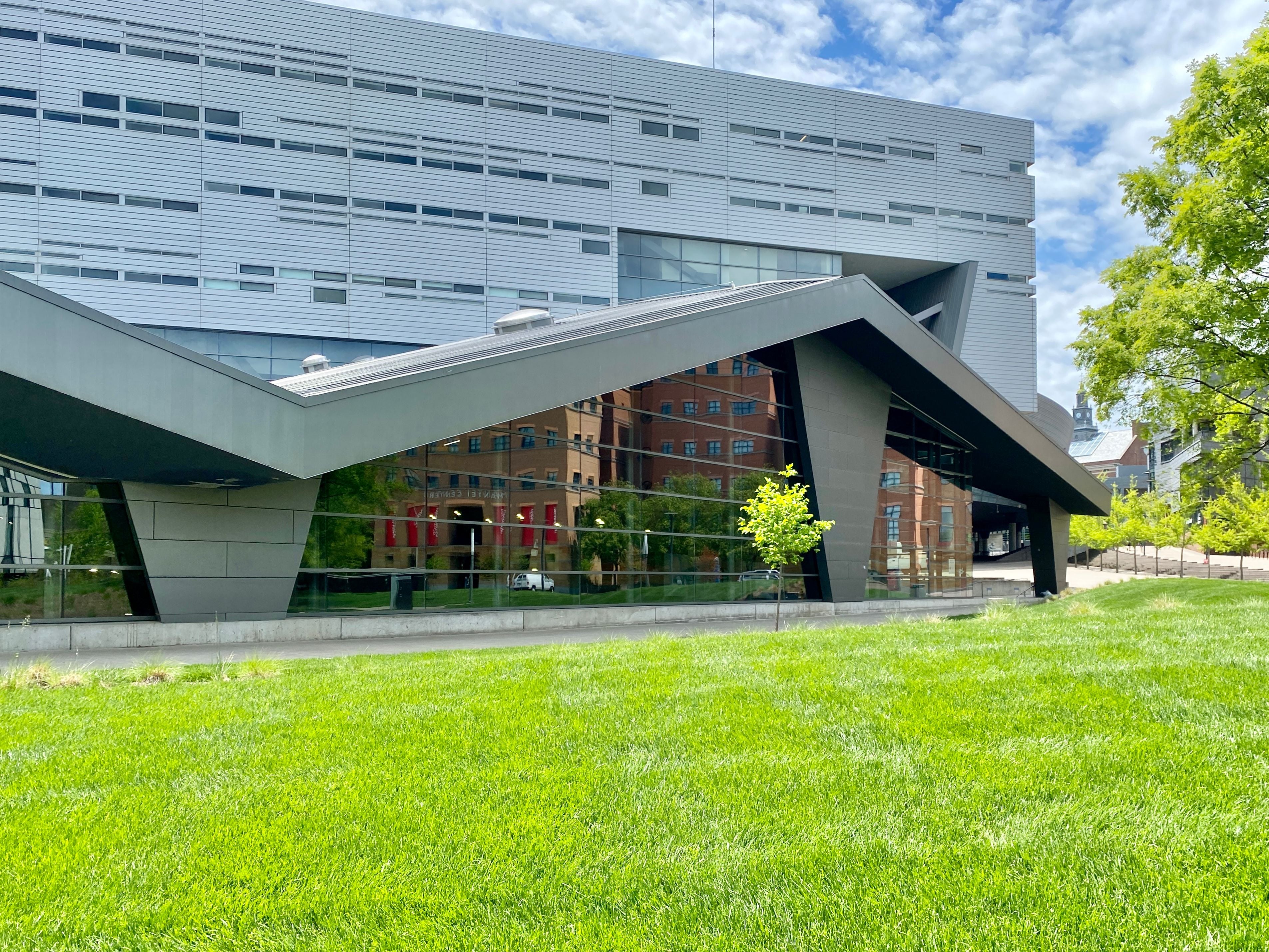Modern building with geometric architectural features and a grassy lawn.