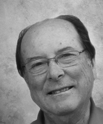 Black and white portrait of a smiling older man wearing glasses.