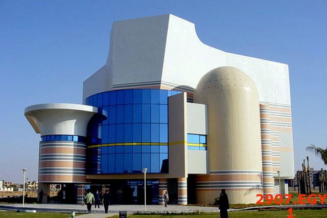 Modern building with blue glass windows, curved cream sections, and geometric white architecture.