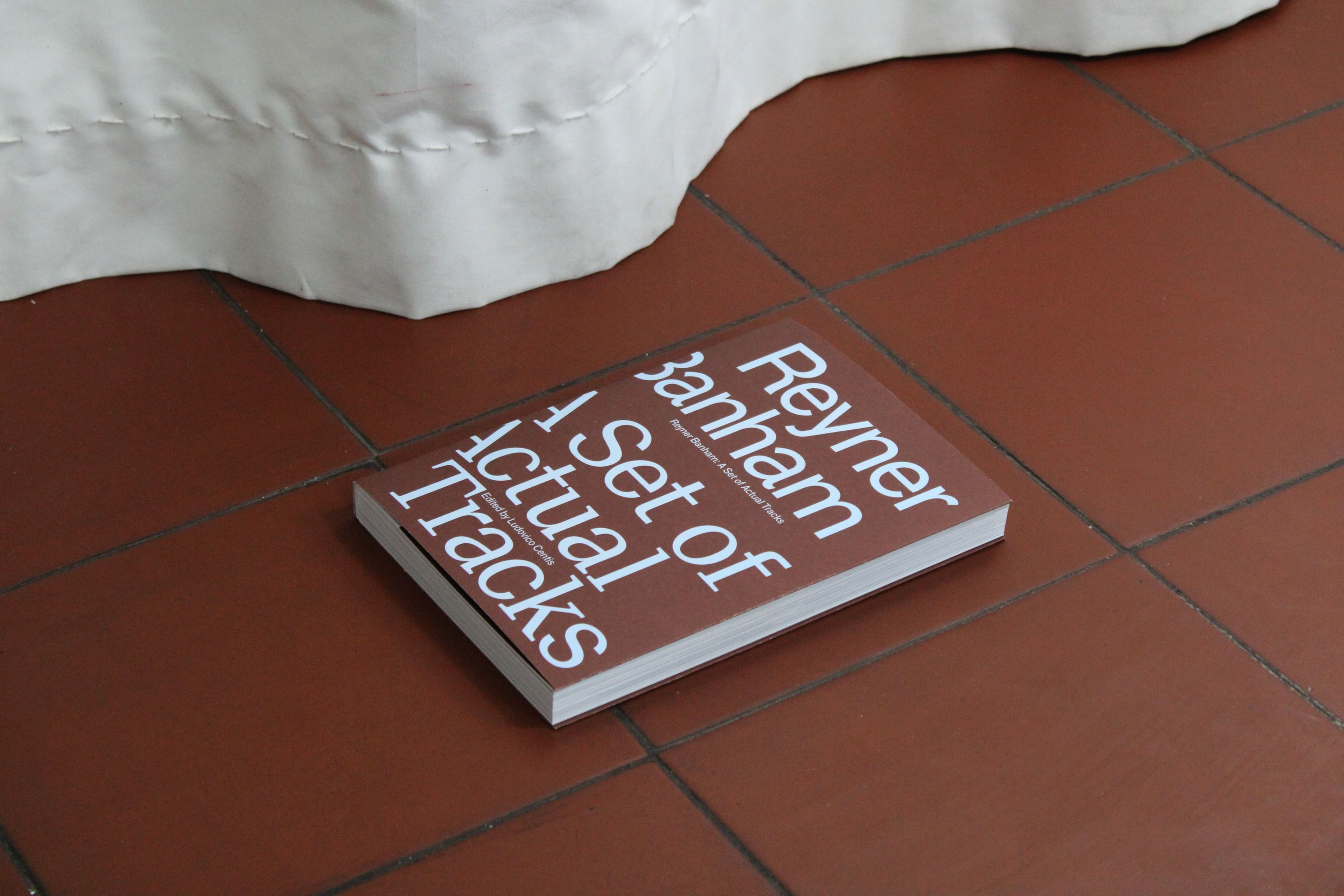 The publication 'Reyner Banham A Set of Actual Tracks' by AA Publications on a brown tile floor.