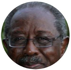 Close-up circular portrait of an older Black man with glasses, looking directly ahead.