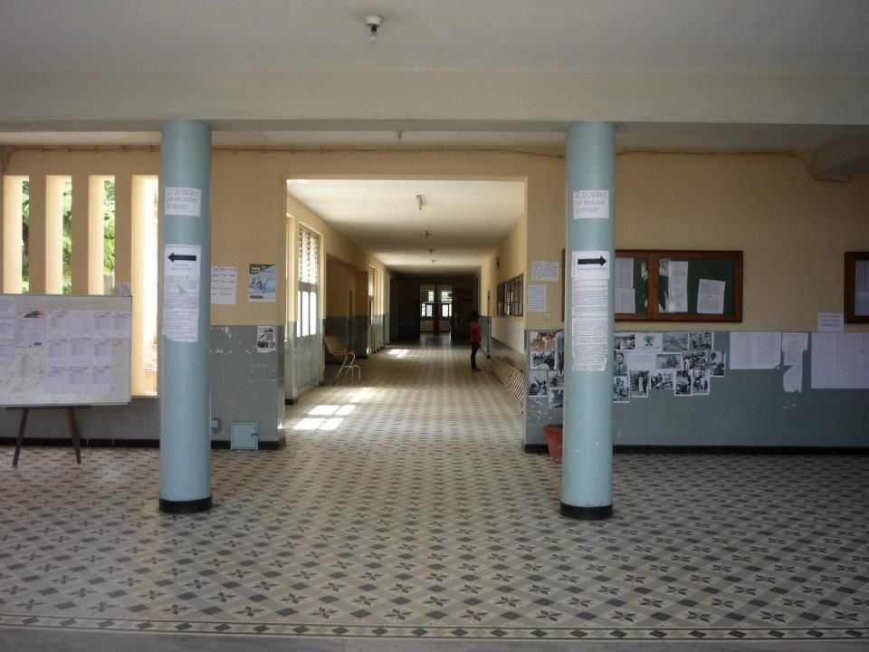 Long, well-lit school hallway with patterned tile floor and two large blue columns.